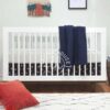 Tempat Tidur Bayi Putih berdesain Scandinavian dengan Kaki dari Kayu Natural.